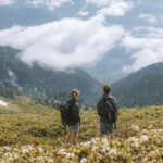 Two hikers with backpacks admire a stunning mountain landscape. Perfect for travel and adventure themes.