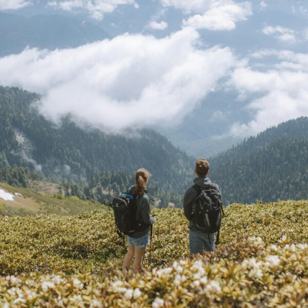 Two hikers with backpacks admire a stunning mountain landscape. Perfect for travel and adventure themes.